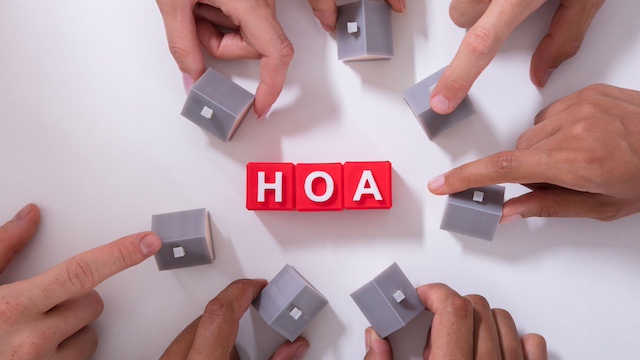 The letters HOA surrounded by people holding small house replicas